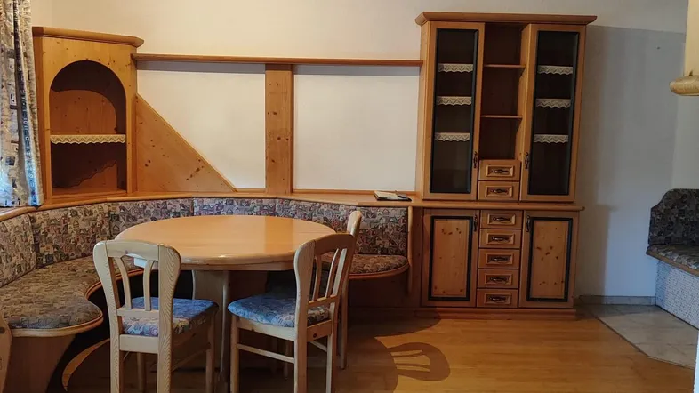 Gemütlicher Wohn-Essbereich im alpinen Stil mit Eckbank, Holztisch und Schrankwand.