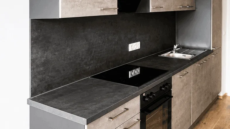 Moderne Einbauküche mit grauen Fronten, dunkler Arbeitsplatte und Holzfußboden.