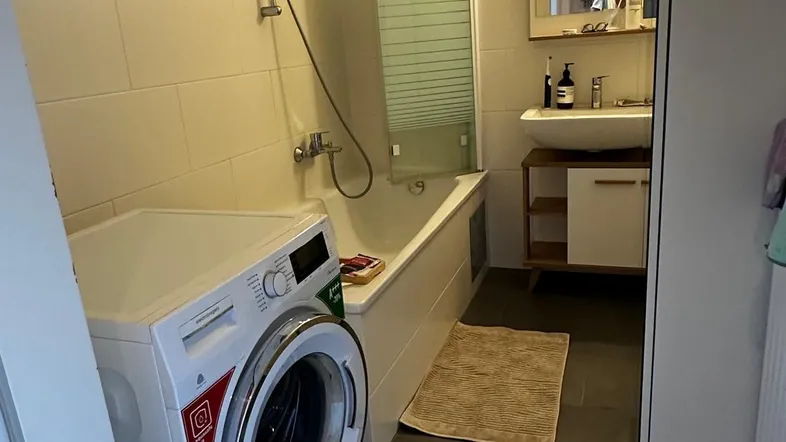Modernes Badezimmer mit Badewanne, Dusche, Waschbecken und integrierter Waschmaschine.