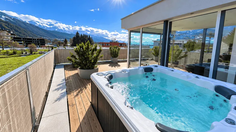 Sonnige Dachterrasse mit Whirlpool, Holzboden und atemberaubendem Bergblick.