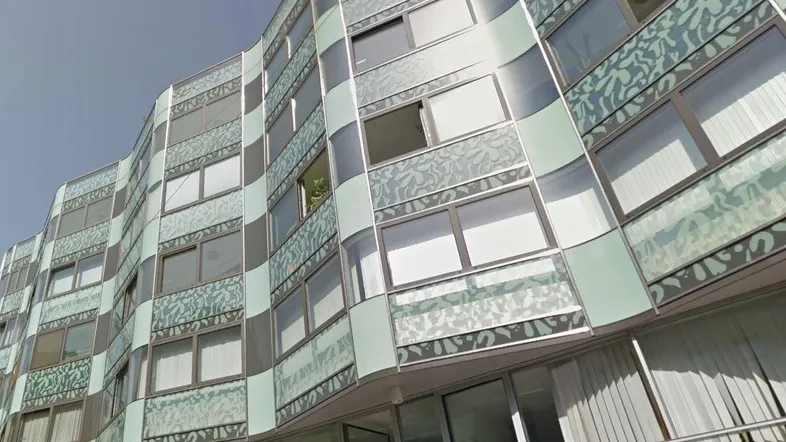 Moderne Fassade eines Gebäudes mit geschwungenen Linien und dekorativen Glaselementen.