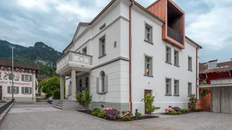 Eindrucksvolles Gebäude mit weißer Fassade, moderner Kupferverkleidung und Bergblick in ländlicher Umgebung.
