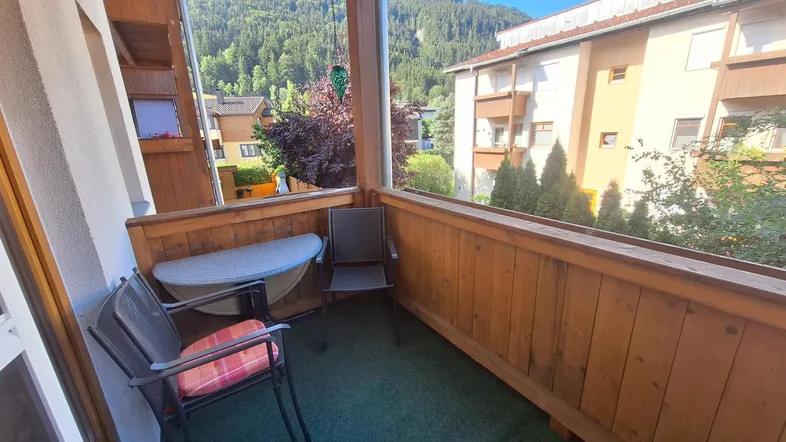 Gemütlicher Balkon mit Holzelementen, Sitzgelegenheiten und Blick auf die umliegende Berglandschaft.