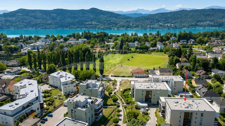 Luftaufnahme der Wohnanlage mit Blick auf den See und die umliegende Berglandschaft.