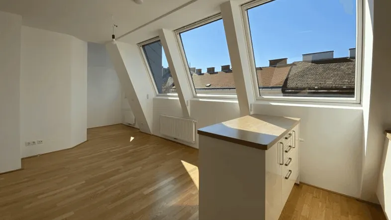 Heller Wohnraum mit Holzboden, Dachschrägenfenstern und Blick über die Dächer der Stadt.