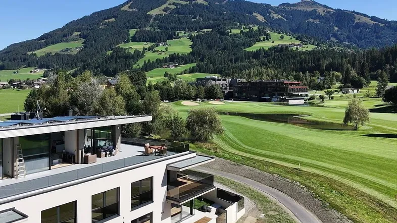 Moderne Architektur mit Dachterrasse, Solaranlage und weitem Blick auf den Golfplatz und die Berge.