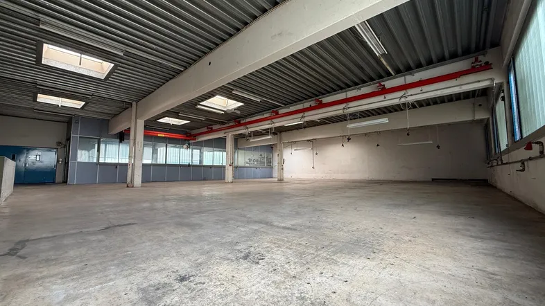 Große, leere Lagerhalle mit Betonboden, hohen Decken und Oberlichtern, bereit zur Nutzung.
