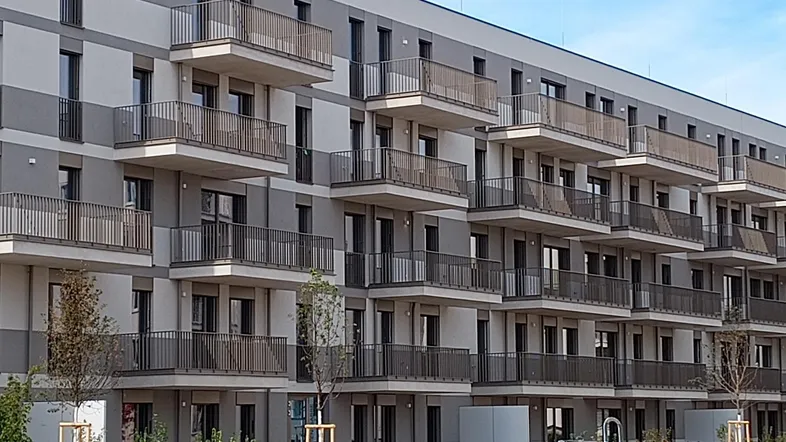 Moderne Wohnanlage mit zahlreichen Balkonen und einer hellgrauen Fassade.
