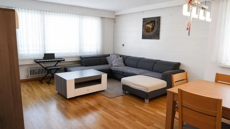 Helles Wohn- und Esszimmer mit Holzboden, großem Sofa und Esstisch.
