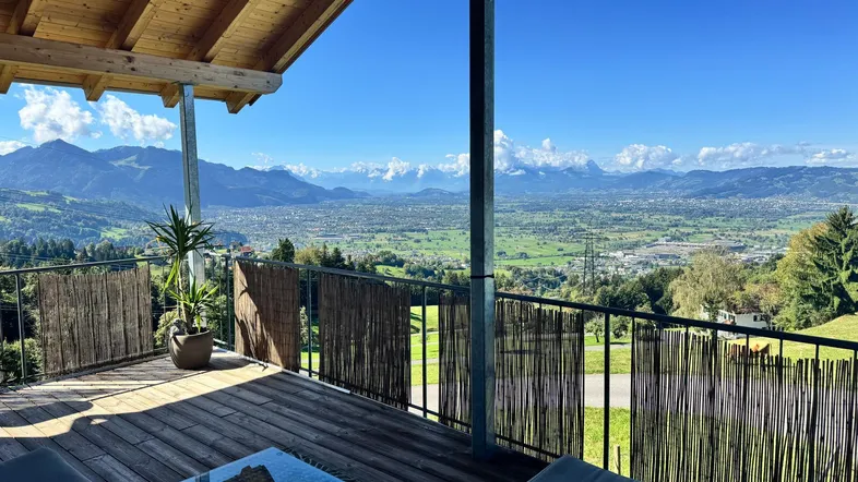 Geräumige Terrasse mit Holzboden, Loungemöbeln und atemberaubendem Panoramablick auf die Berge und das Tal.