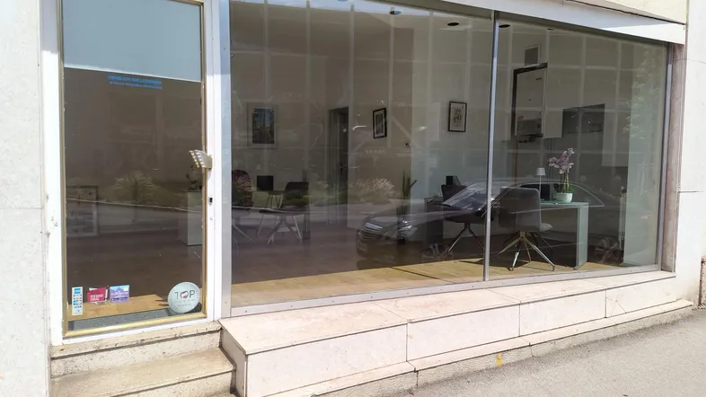 Eingangsbereich eines Geschäftsgebäudes mit großer Glasfront, die den Blick ins helle Innere freigibt.