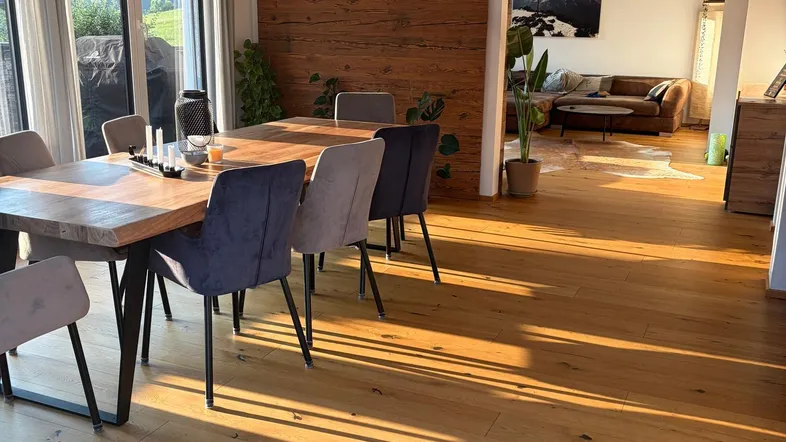 Heller Essbereich mit großem Holztisch und Zugang zum Wohnzimmer, durchflutet von natürlichem Sonnenlicht.