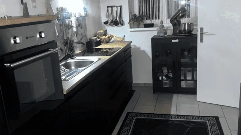 Moderne Küche mit schwarzen Schränken, integriertem Backofen und einem Fenster über der Spüle.
