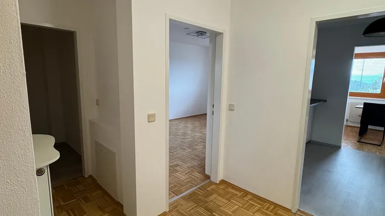 Heller Flur mit Parkettboden, der zu verschiedenen Zimmern der Wohnung führt.