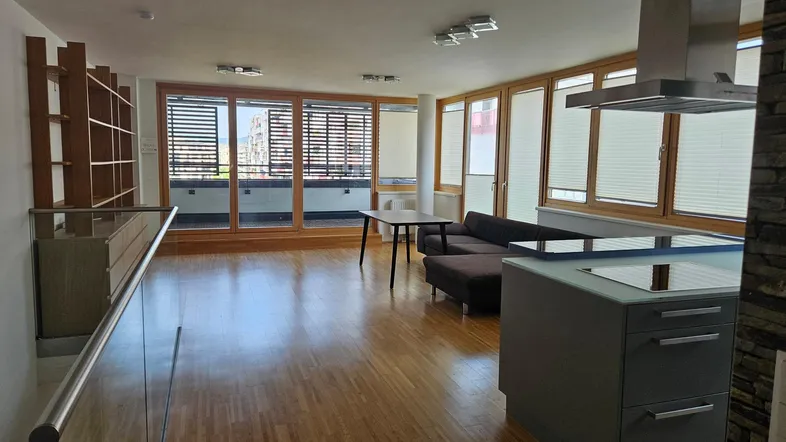 Helles Wohn-Esszimmer mit Holzboden, offener Küche und Zugang zu einem Balkon.