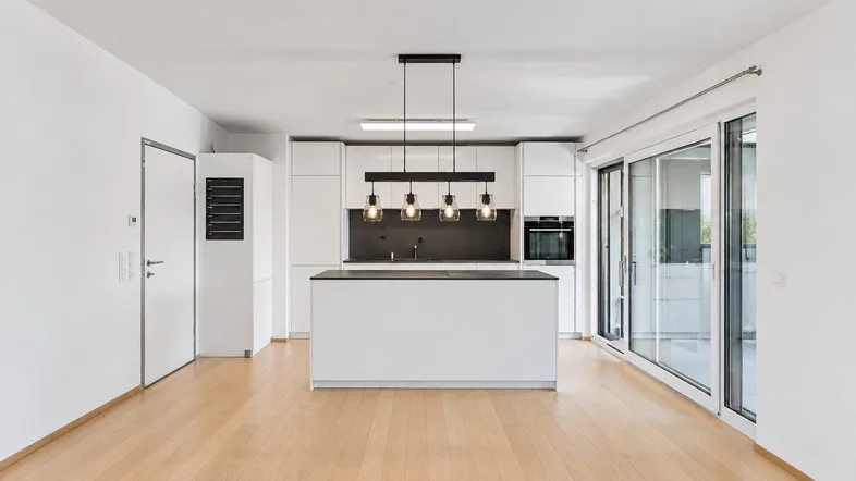Moderne offene Küche mit weißer Kücheninsel, Einbaugeräten und Zugang zur sonnigen Terrasse.