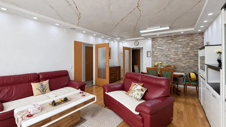 Geräumiger Wohn- und Essbereich mit roten Ledersofas, Holzboden und dekorativer Steinwand.