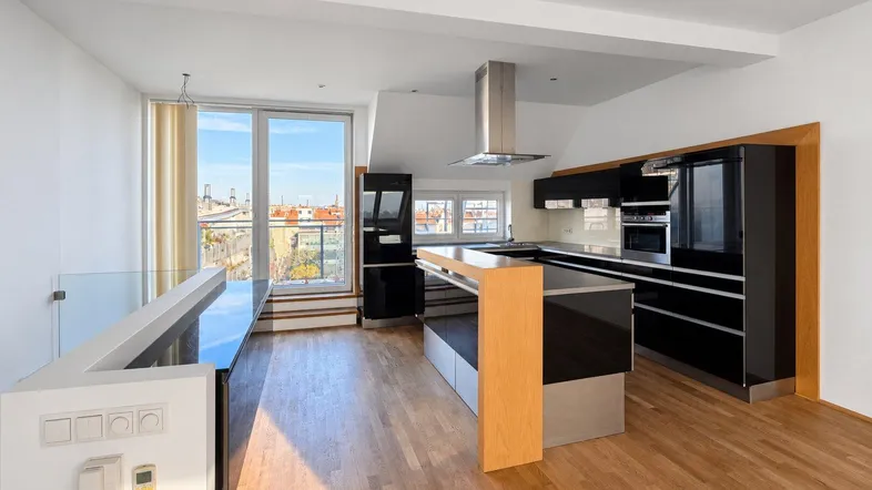 Moderne offene Küche mit schwarzen Hochglanzfronten, Holzboden und Zugang zu einem Balkon mit Stadtblick.
