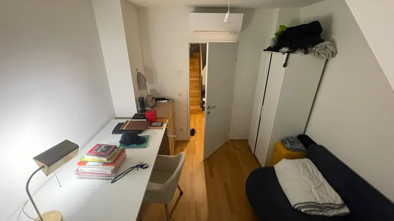 Helles Zimmer im Dachgeschoss mit Schreibtisch, Sofa und Schrank, ideal als Schlaf- oder Arbeitszimmer.