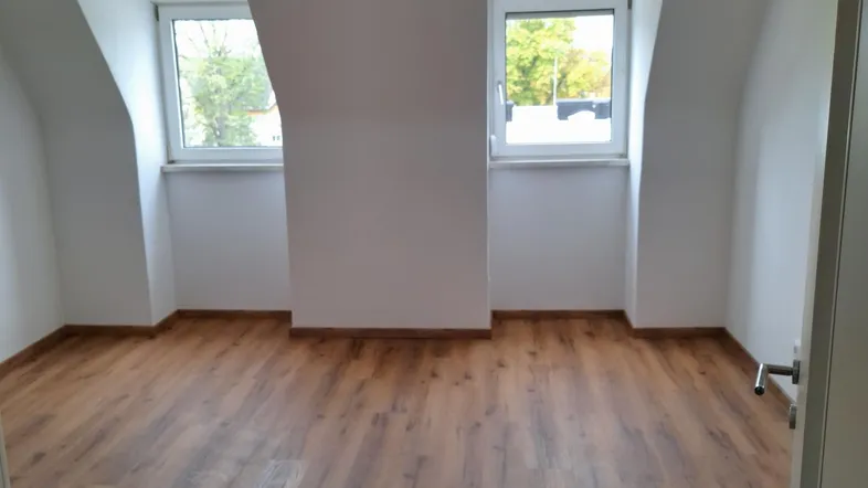 Helles Zimmer im Dachgeschoss mit Laminatboden und zwei Fenstern, ideal als Schlafzimmer nutzbar.