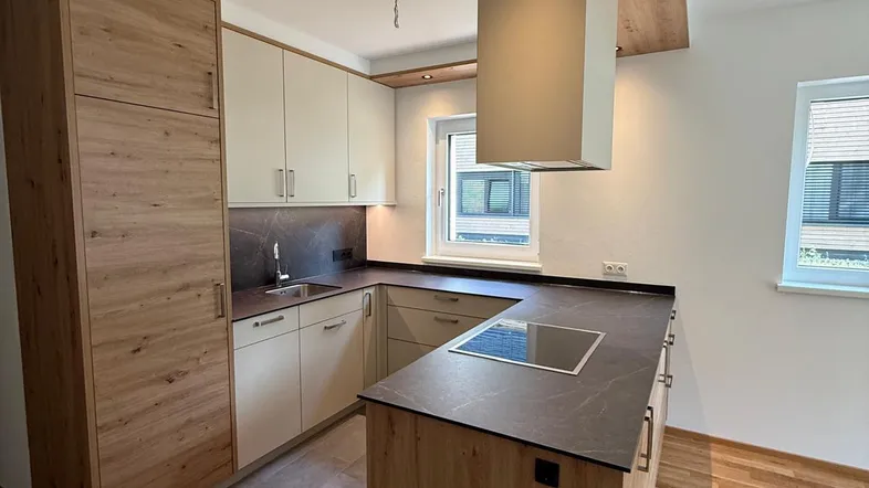 Moderne Einbauküche mit Holzfronten, Kochinsel und integriertem Induktionskochfeld in hellem Raum.