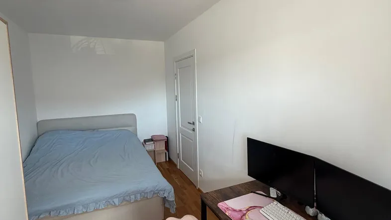 Helles Schlafzimmer mit Holzboden, einem Bett und einem modernen Schreibtischbereich.