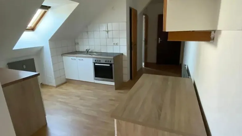 Helle Dachgeschossküche mit einfacher Küchenzeile, Holzfußboden und einem Dachfenster für natürliches Licht.