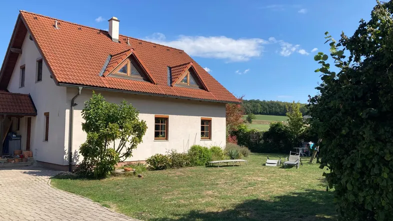 Freistehendes Haus mit rotem Ziegeldach, großem Garten und weitem Blick auf die umliegende Landschaft.