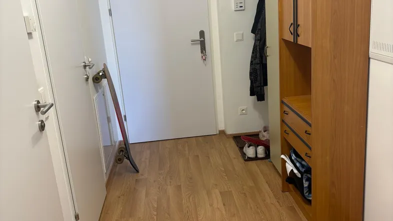 Heller Eingangsbereich mit Laminatboden und praktischem Holzschrank für Garderobe und Stauraum.