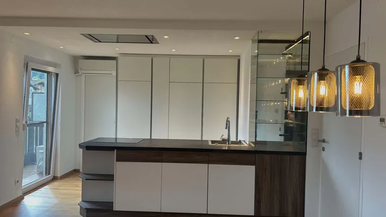 Moderne offene Küche mit Kochinsel, Holzboden und Zugang zum Balkon.