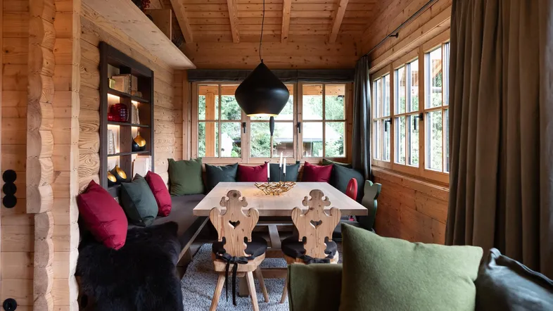 Gemütlicher Essbereich im alpinen Stil mit Holzwänden, Holzbalkendecke und bequemer Sitzbank.