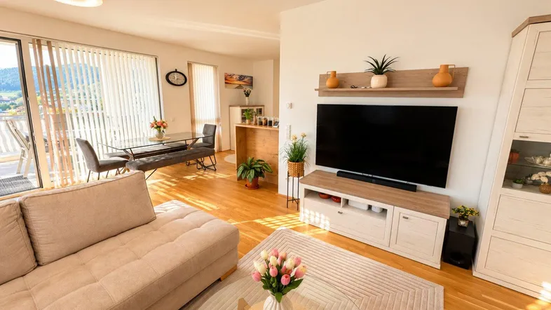 Helles Wohn- und Esszimmer mit Holzboden, bequemer Couch und Zugang zum Balkon.