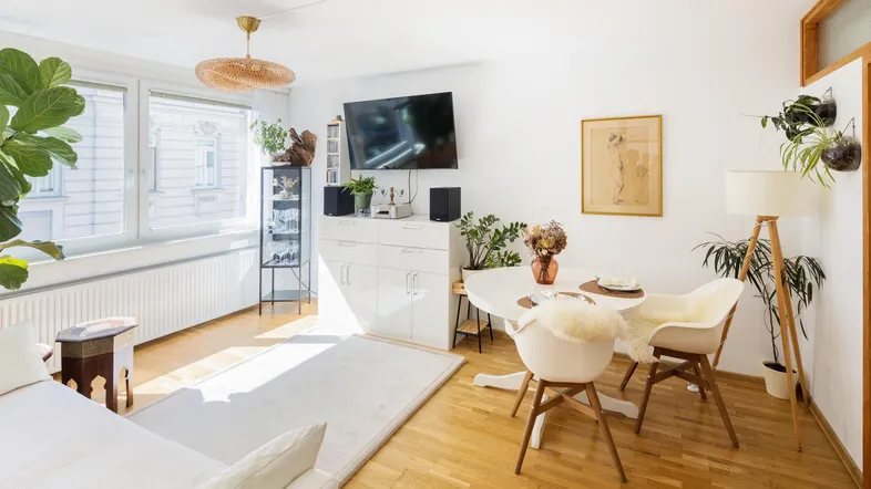 Helles Wohnzimmer mit Essbereich, Holzboden, großen Fenstern und moderner Einrichtung.