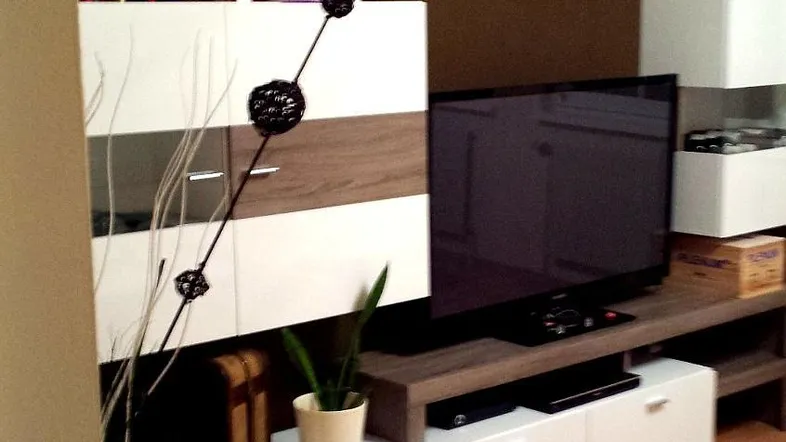 Gemütliches Wohnzimmer mit modernem Medienmöbel, brauner Akzentwand und hellem Holzfußboden.