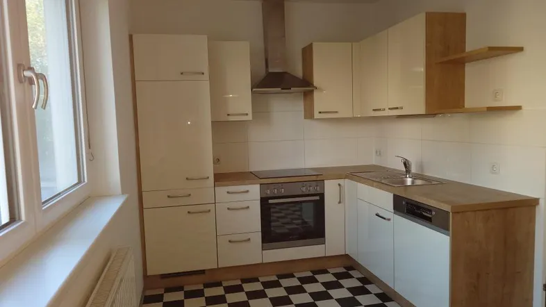 Moderne Küche mit weißen Schränken, Holz-Arbeitsplatten und markantem schwarz-weißem Fliesenboden.