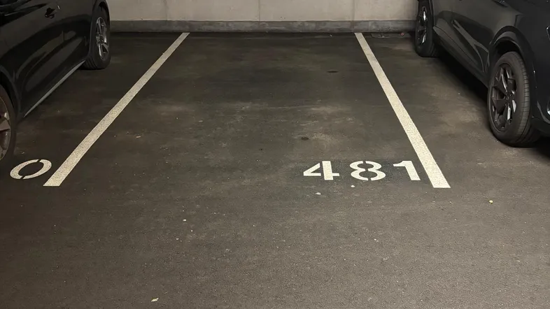 Tiefgaragenstellplatz Nummer 481 mit Betonwänden und Asphaltboden in einem gepflegten Zustand.