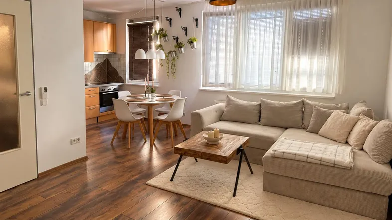 Heller offener Wohn- und Essbereich mit integrierter Küche und gemütlichem Sofa.