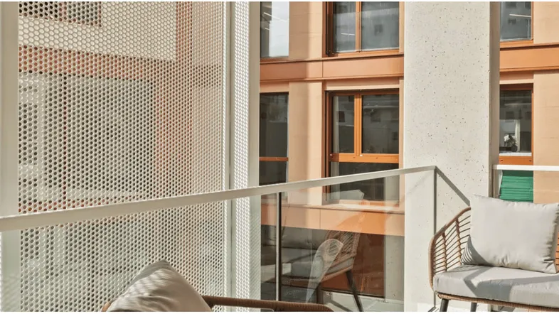Moderner Balkon mit Sitzgelegenheiten und Blick auf die umliegenden Gebäude der Stadt.