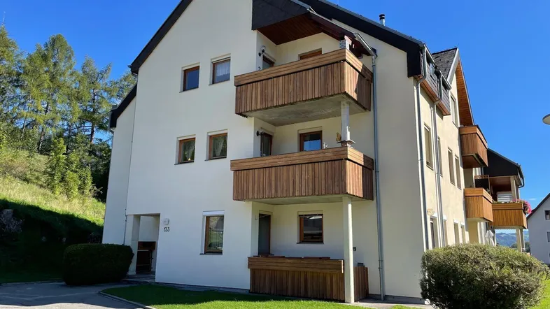 Mehrfamilienhaus mit Balkonen und gepflegter Fassade in alpiner Umgebung.