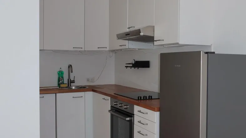 Moderne Küche mit weißen Schränken, Holzarbeitsplatte und integrierten Geräten.