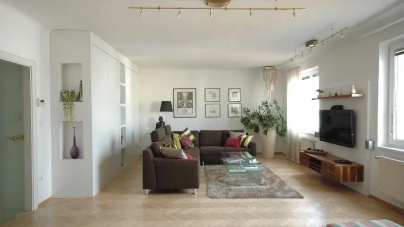 Helles Wohnzimmer mit Parkettboden, bequemen Sofas und moderner Wanddekoration.