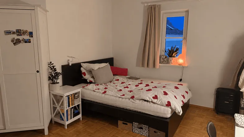 Gemütliches Schlafzimmer mit Einzelbett, Parkettboden und weißem Kleiderschrank.
