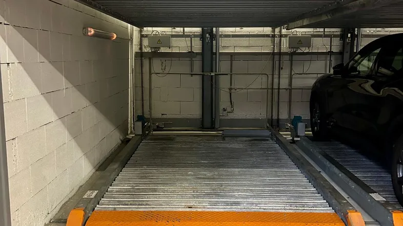 Automatisches Parksystem in einer Tiefgarage mit doppelstöckigen Stellplätzen und Betonwänden.