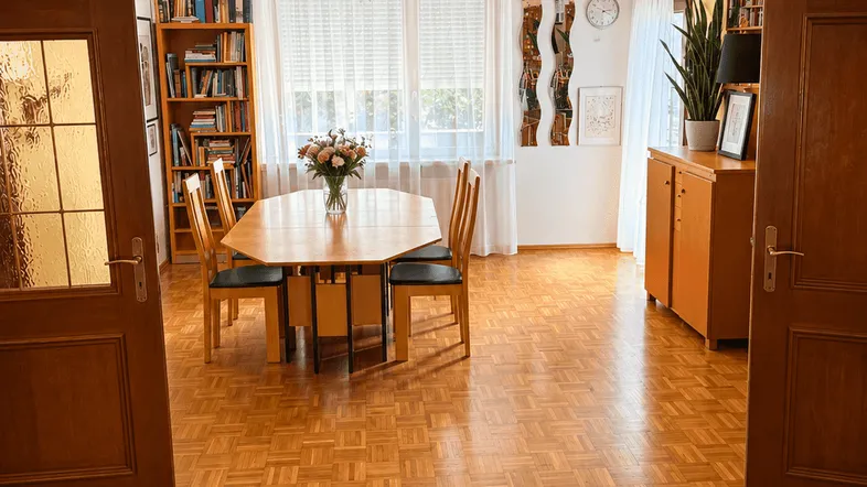 Heller Essbereich mit Parkettboden, großem Esstisch und Bücherregalen, ideal für gesellige Runden.
