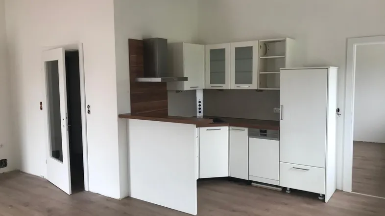 Moderne Einbauküche in Weiß mit Holzdetails und integrierten Geräten in einem offenen Wohnbereich.