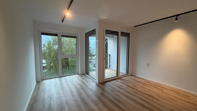 Helles Wohnzimmer mit modernem Laminatboden und Zugang zu einem kleinen Balkon.