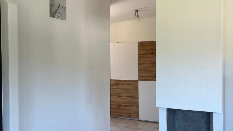 Heller Innenbereich mit Fliesenboden und modernem Kamin, der zu weiteren Räumen führt.
