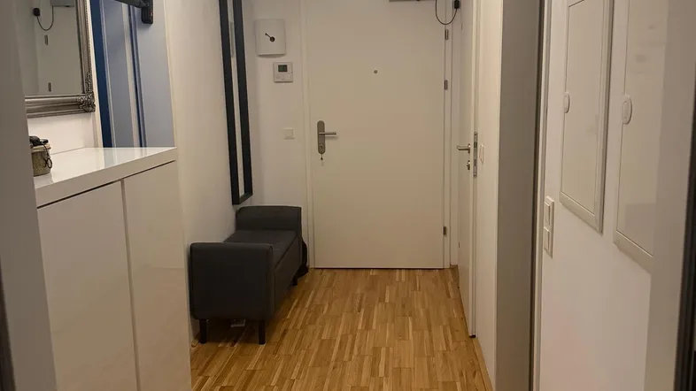 Helle Diele mit Holzparkettboden, weißem Schuhschrank und einer Sitzbank am Eingangsbereich.