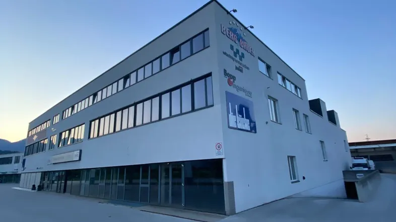 Modernes Geschäftsgebäude mit mehreren Etagen und großen Fenstern unter einem klaren Himmel bei Dämmerung.
