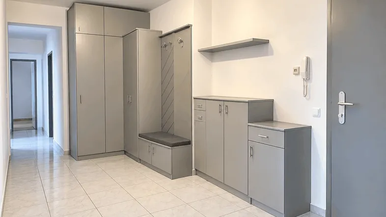 Heller Flur mit grauen Einbauschränken, Garderobe und praktischem Fliesenboden.